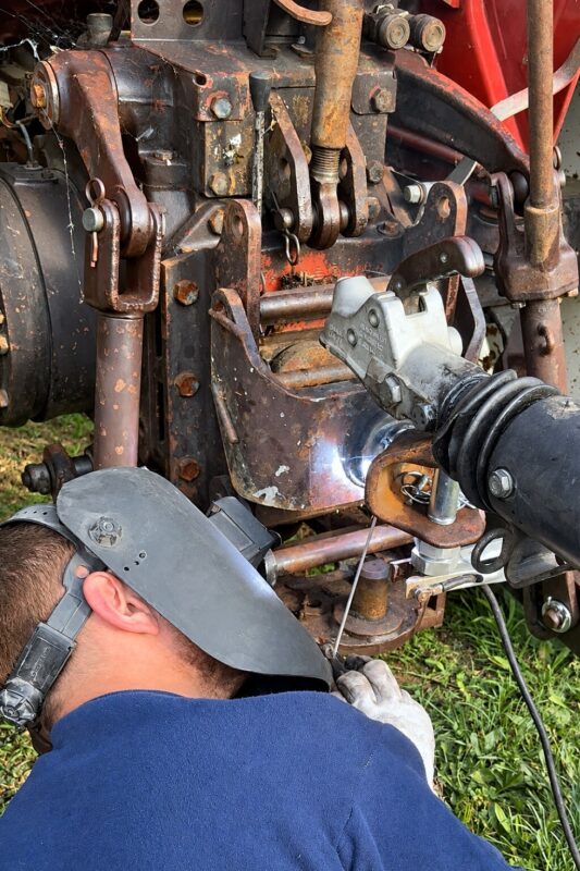 Soudeur au travail sous un engin, casque de soudage